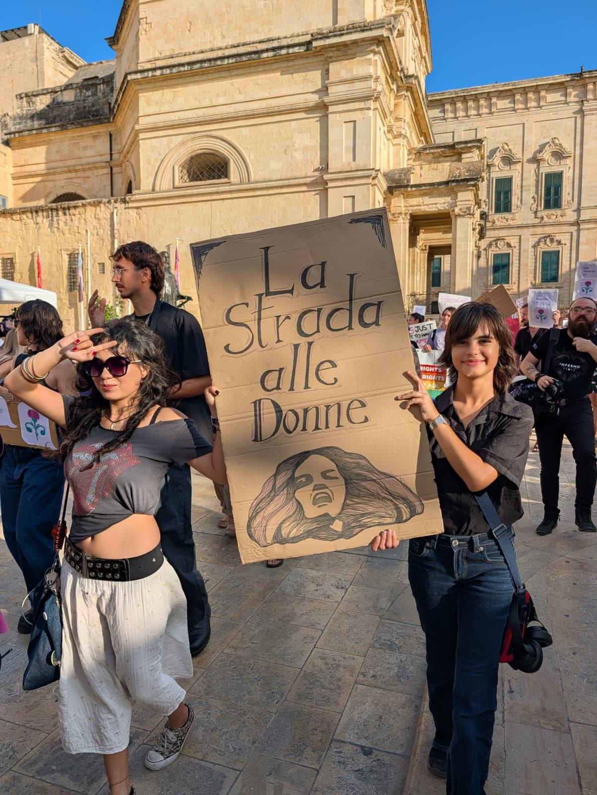 Two protestors holding a placard reading "The road for women" in Italian. Photo: Christian Sant Fournier